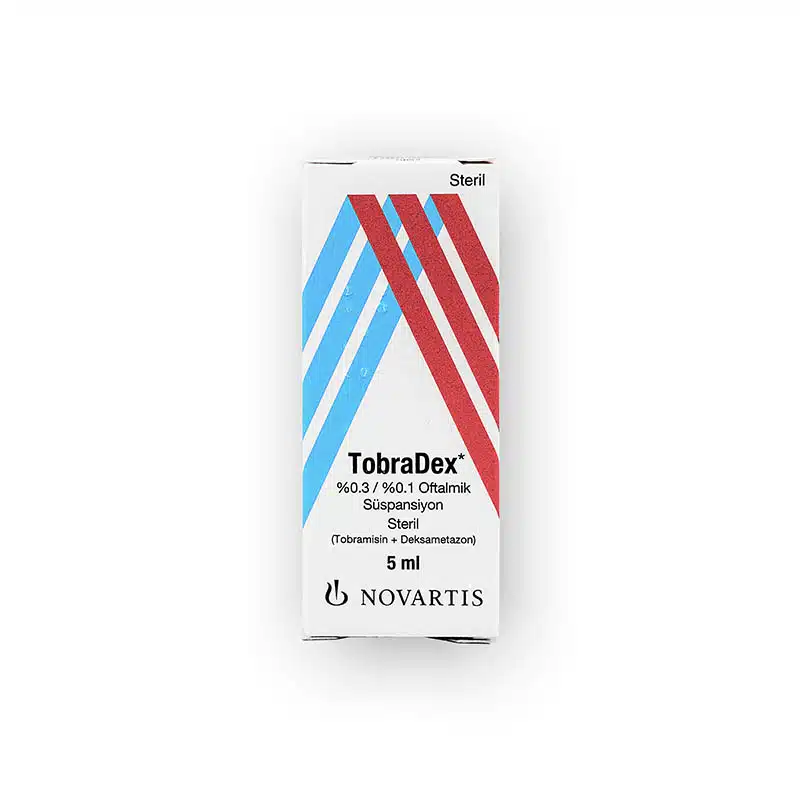 A 5 ml box of TOBRADEX® OPHTHALMIC SUSPENSION 0.3%, 0.1% (non-English) from Novartis. The box features a white background with blue and red diagonal stripes and black text detailing the medication's name and contents (Tobramycin and Dexamethasone).