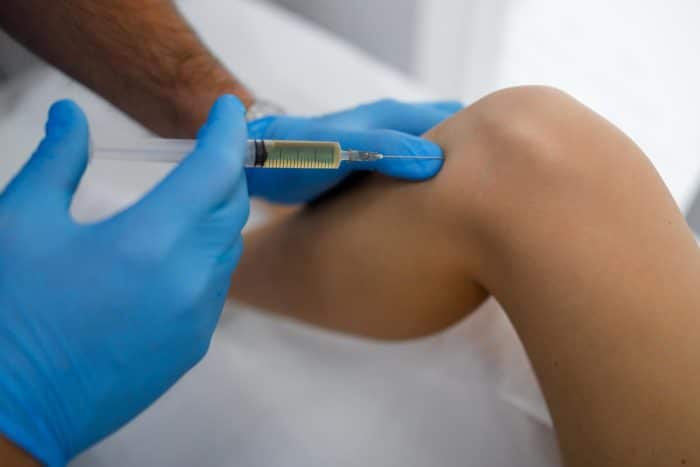 Close up view of a healthcare professional administering knee injection.