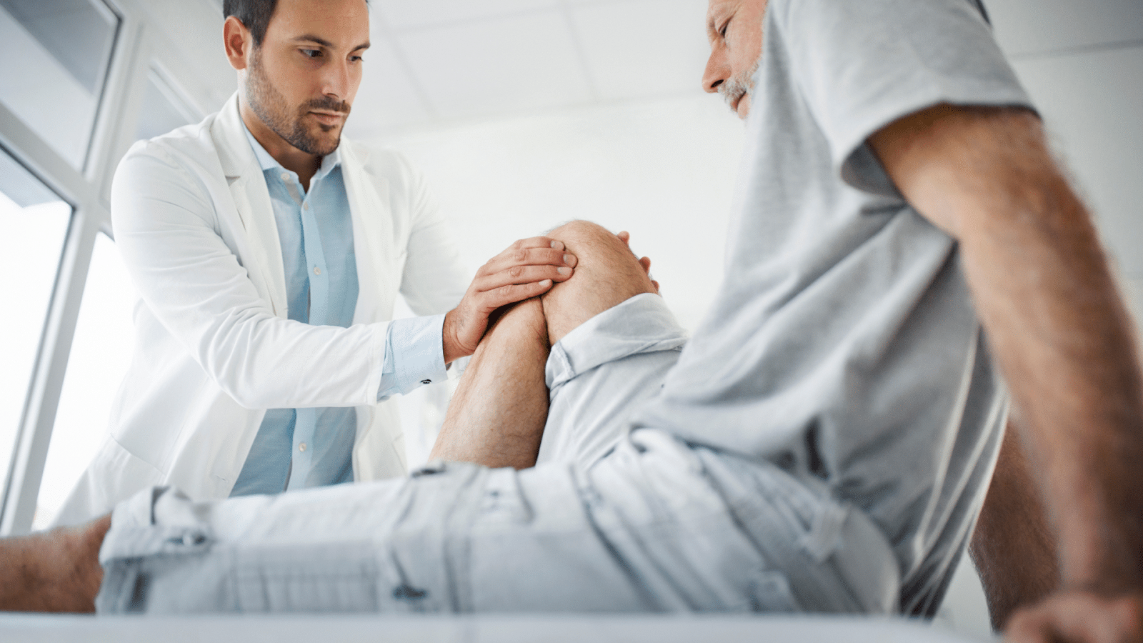A healthcare provider assesses a male patient's knee joint.