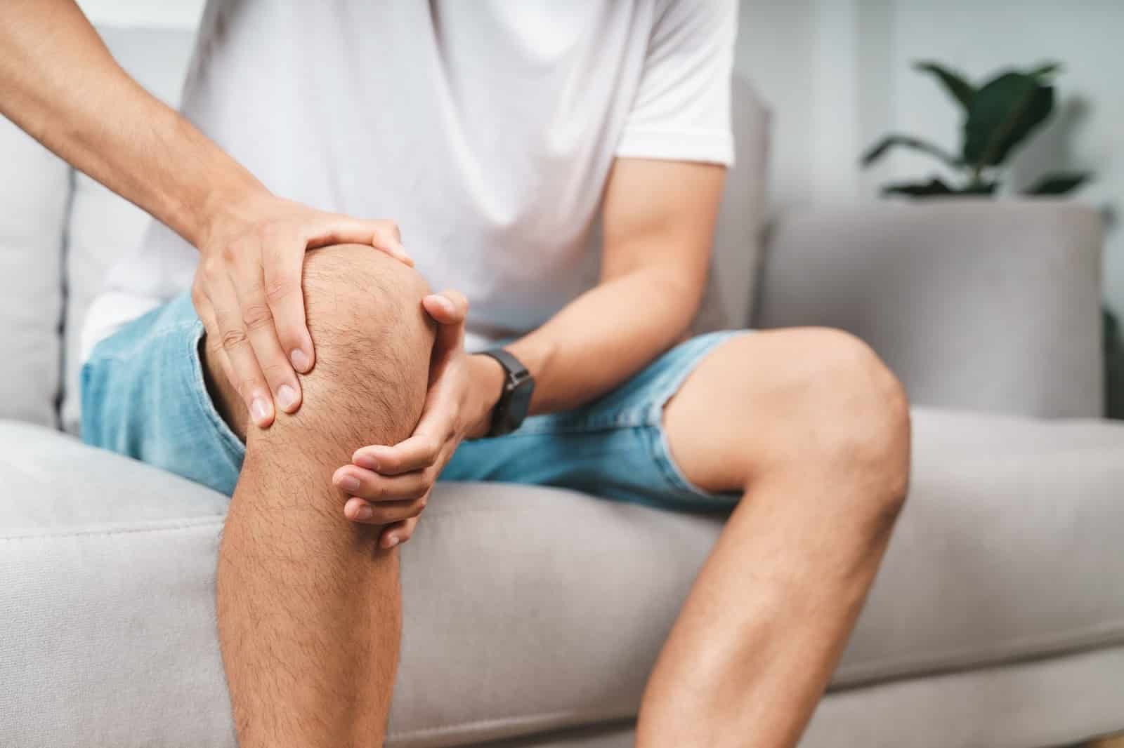 A person grasps at their knee joint after feeling pain caused by osteoarthritis.