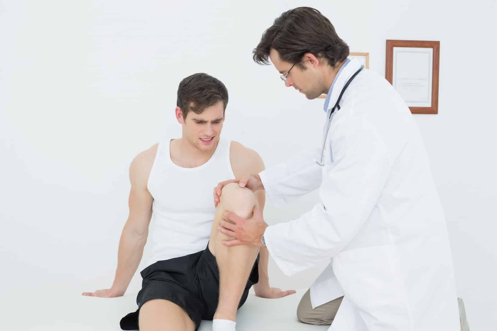 A healthcare professional consulting a male athlete after he experienced pain in the knee joint.