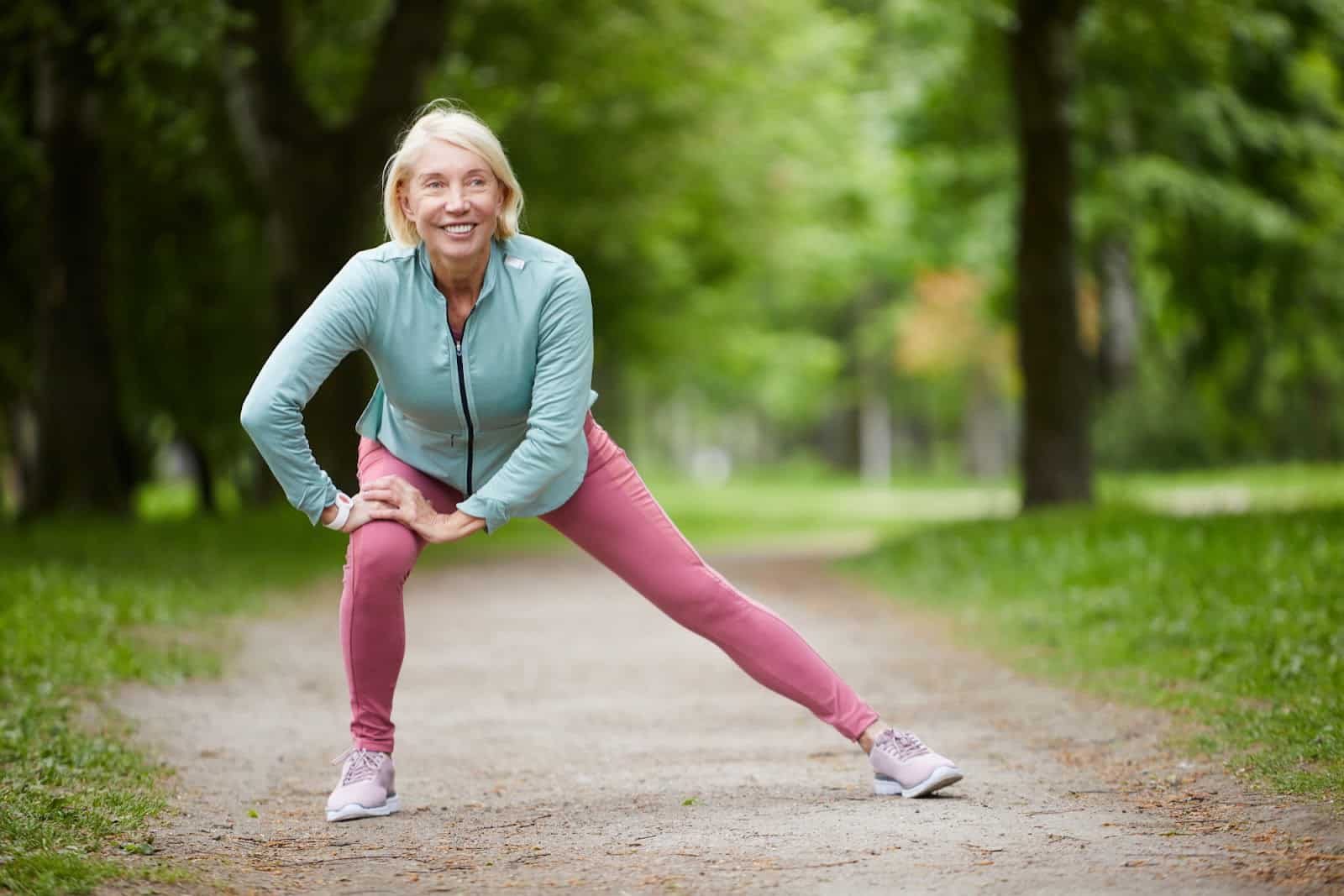A woman at a park, stretching her knees before going on a run.