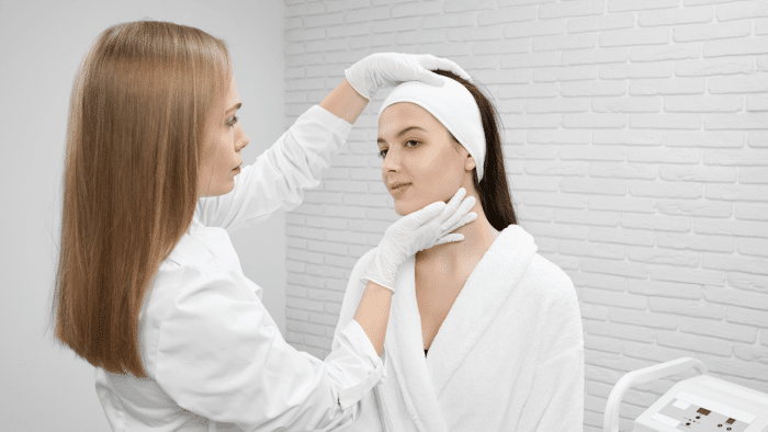 Doctor assessing a woman's face before Hyacorp filler treatment.