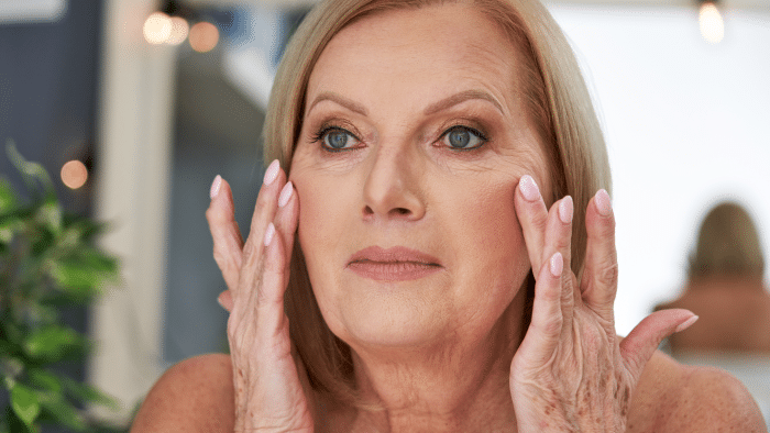 Woman checking out her facial wrinkles in the mirror.