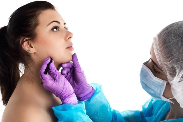 An aesthetic specialist inspects and marks a patient's face to determine the injection sites and dosage for Dysport treatment.