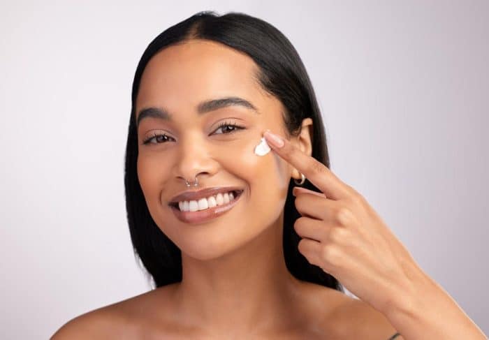 Woman applying topical cream to her face after getting Dysport to minimize and manage bruising.