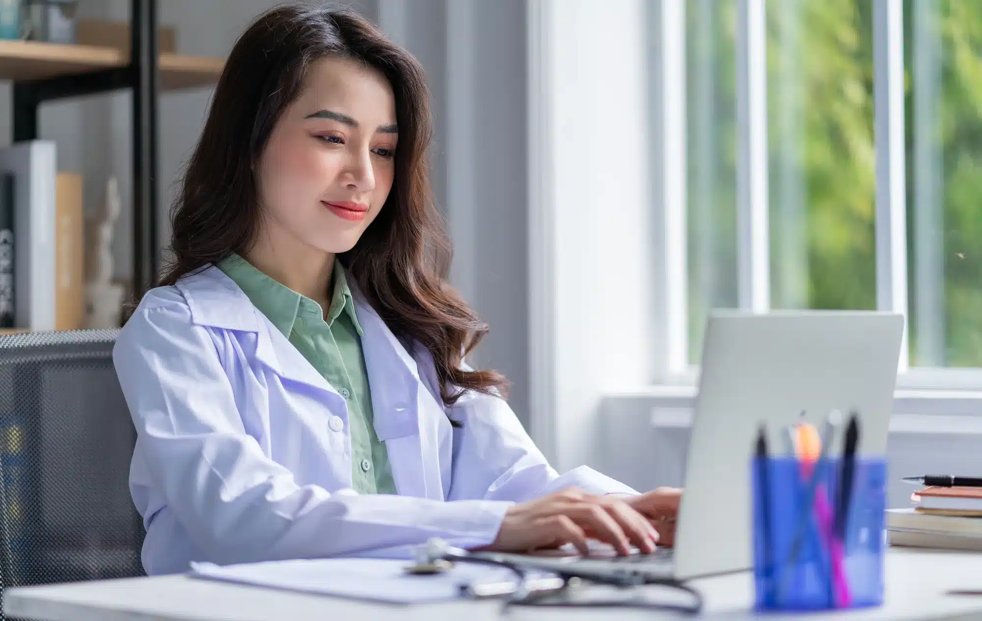 Young female doctor exploring the possibilities for orthopedic advertising on her laptop