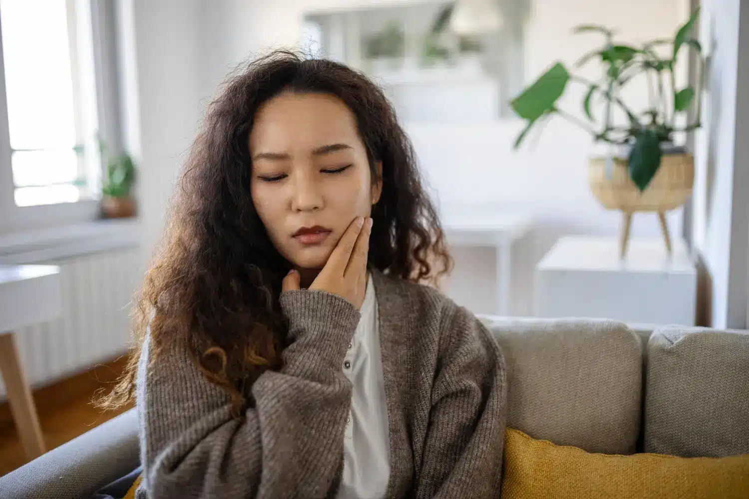Woman holding cheek after feeling pain