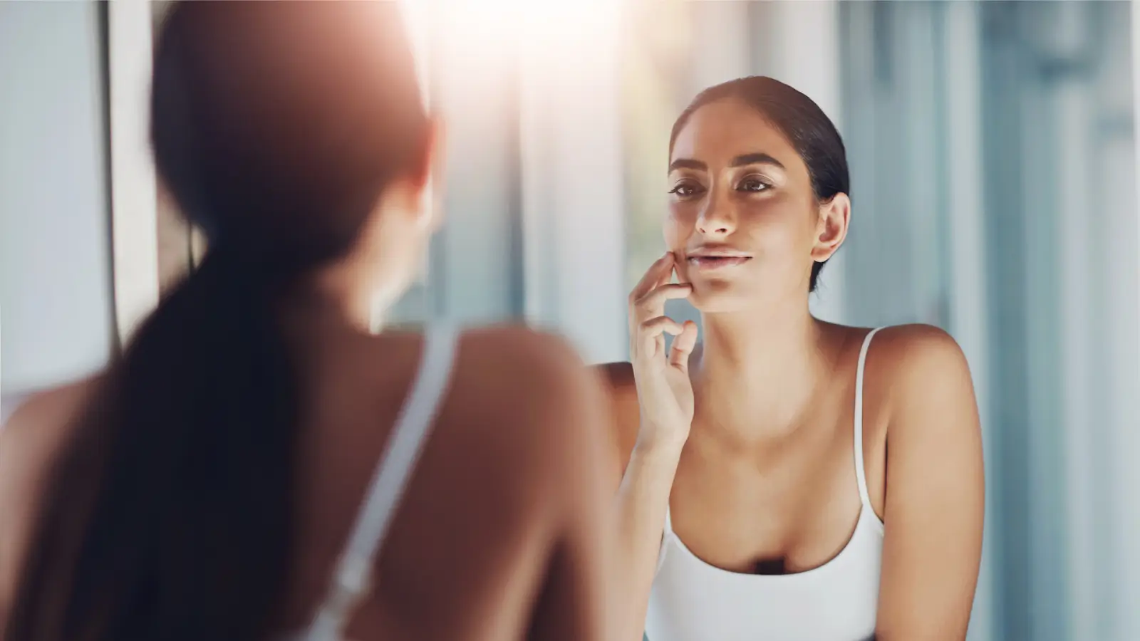 Woman checking the condition of her skin in the mirror.