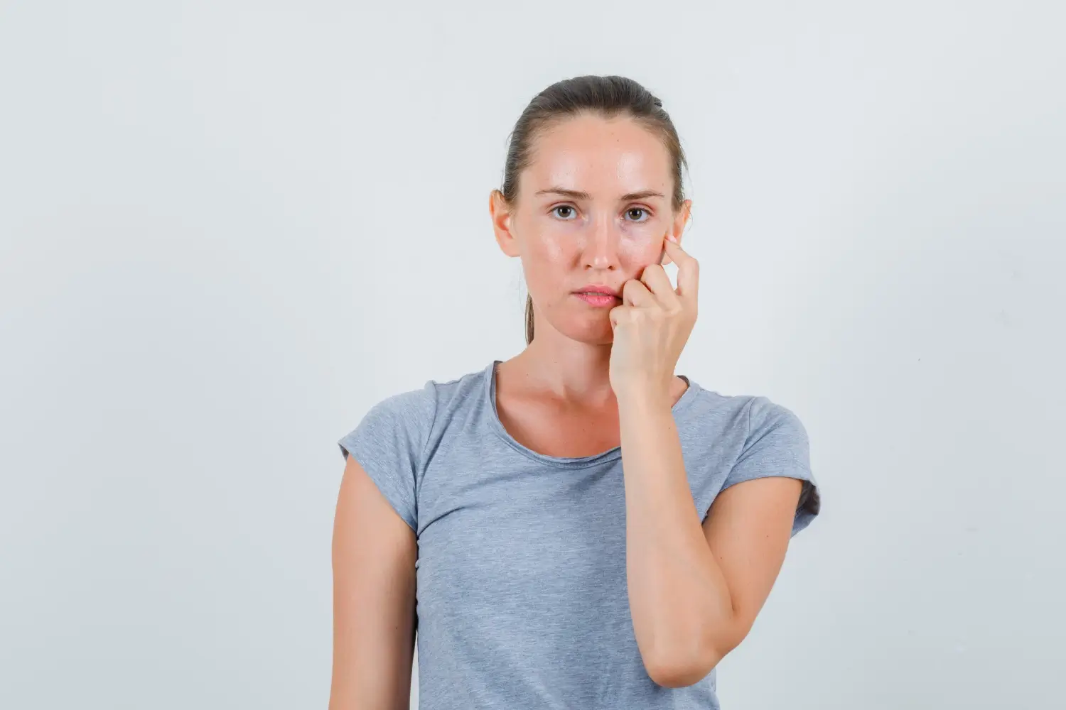 A woman gently touches her cheek after filler treatment.