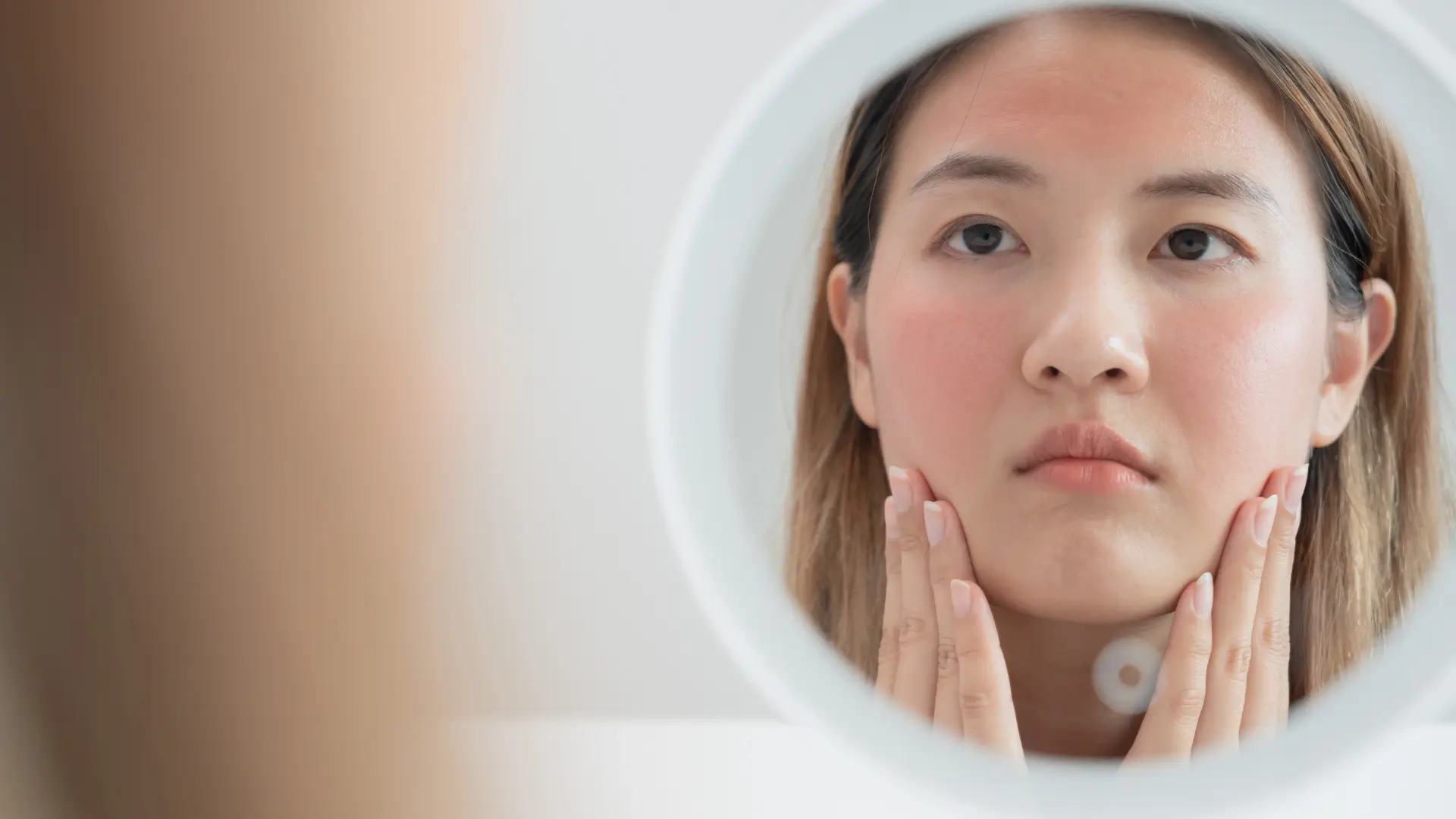 Woman checking skin in the mirror for lumps after filler treatment