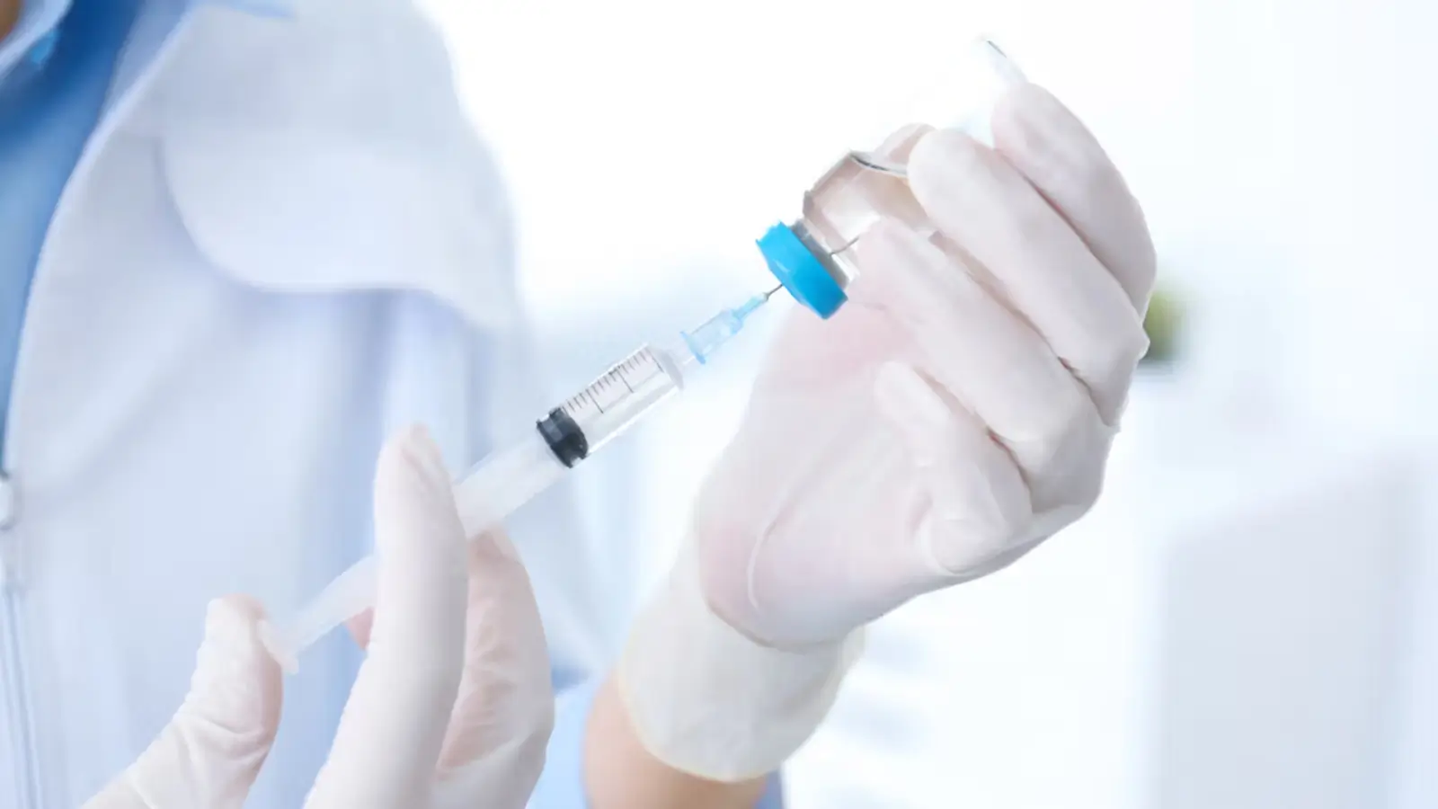 Person extracting medicine from vial.