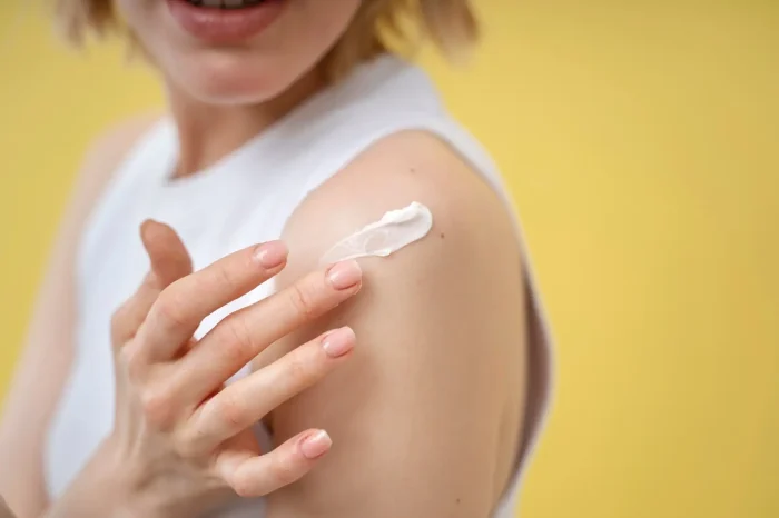 Person putting cream on shoulder.