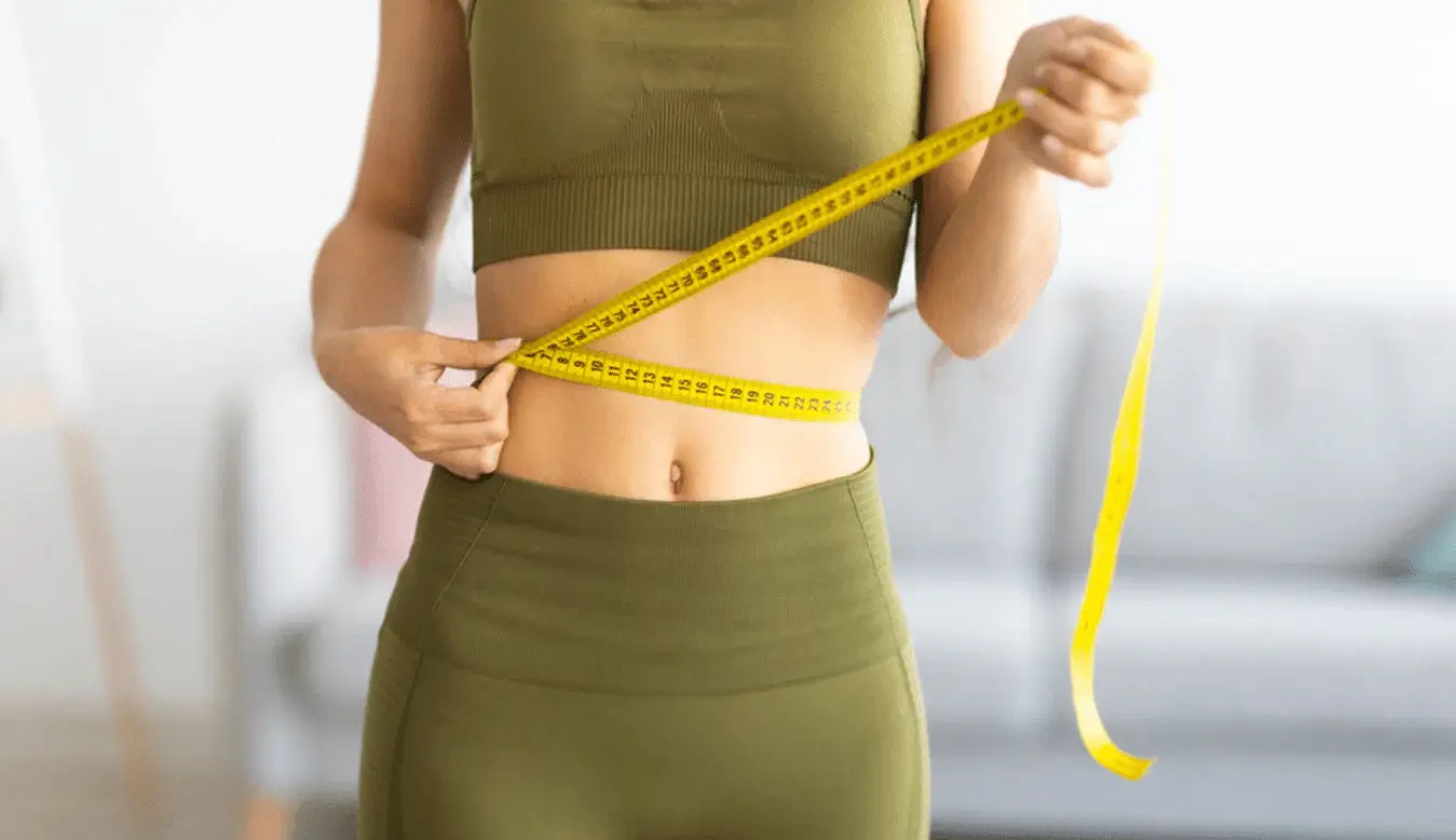 A person holding a tape measure around the waist. 