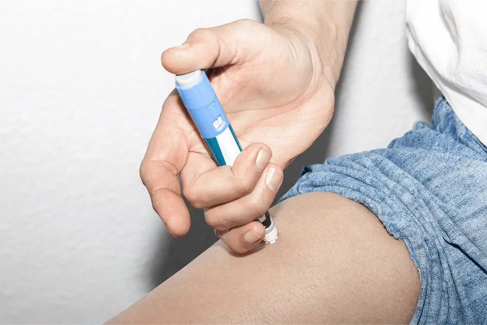 Person using the proper injection technique on their thigh with an injection that is similar to Mounjaro.