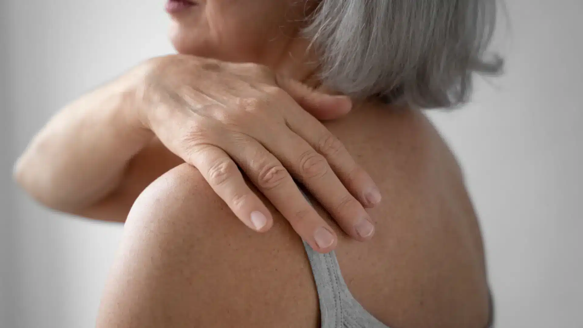 A woman holding her shoulder. She is feeling the effects of the Evenity treatment. 